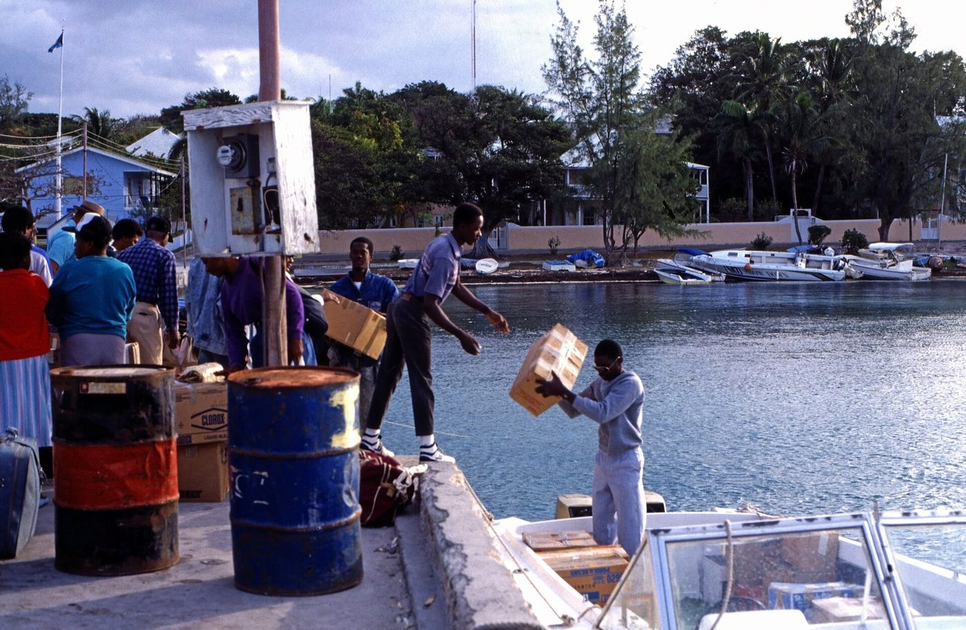 Men unloading oil drums and freight from the mailboat at Governor's Dock, Dunmore Town