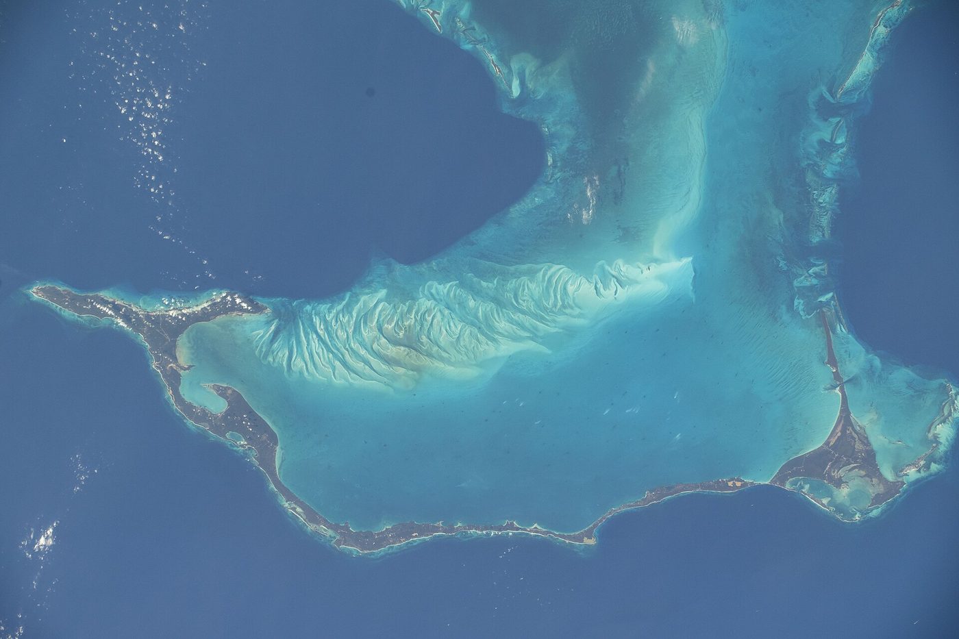 Eleuthera seen from orbit, a long thin island between deep ocean and shallow bank